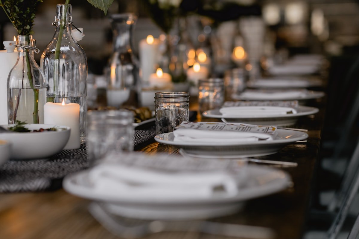 Long dinner table glowing with clusters of lit candles