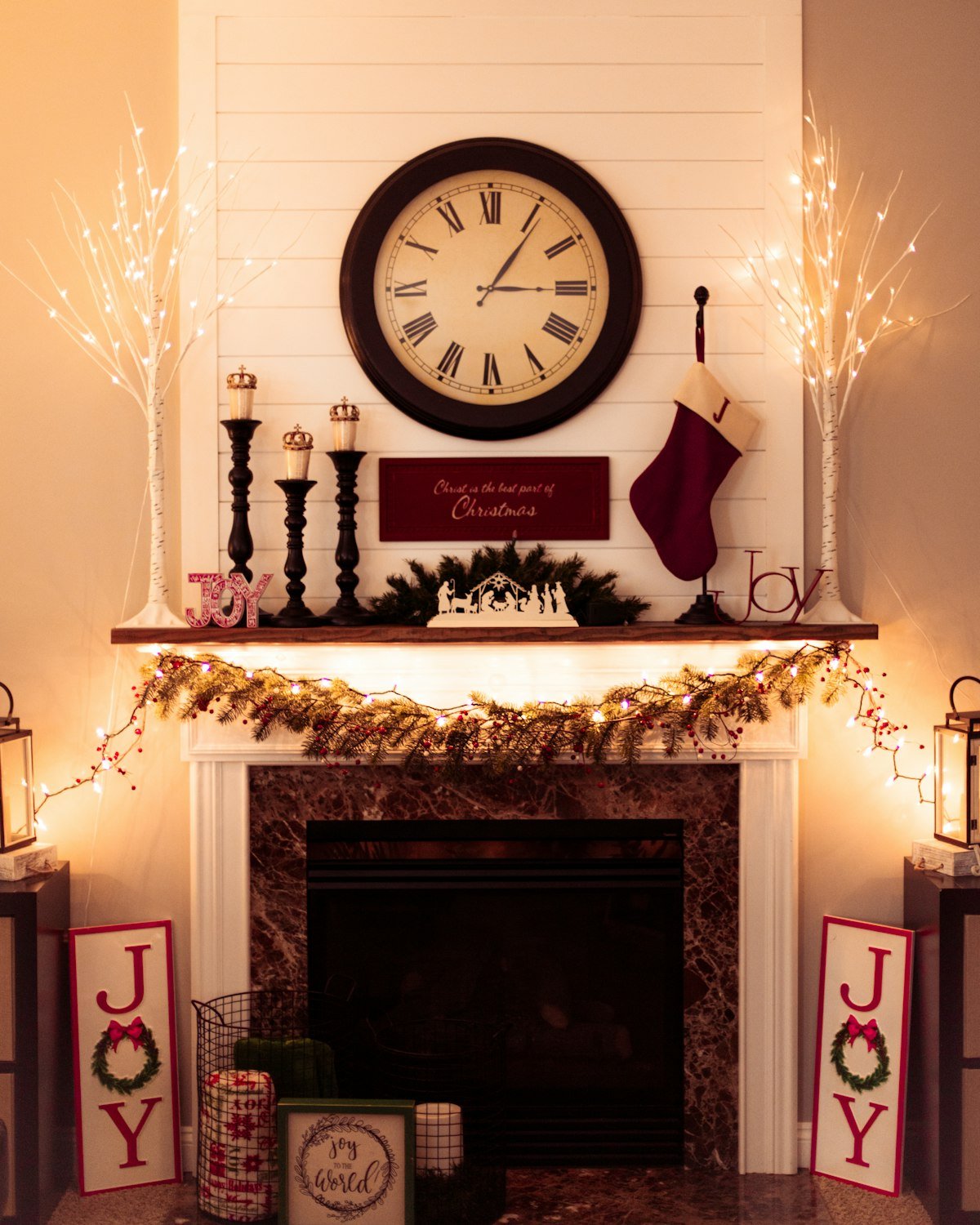 Mantel dressed with evergreen garland, candles, and a stocking