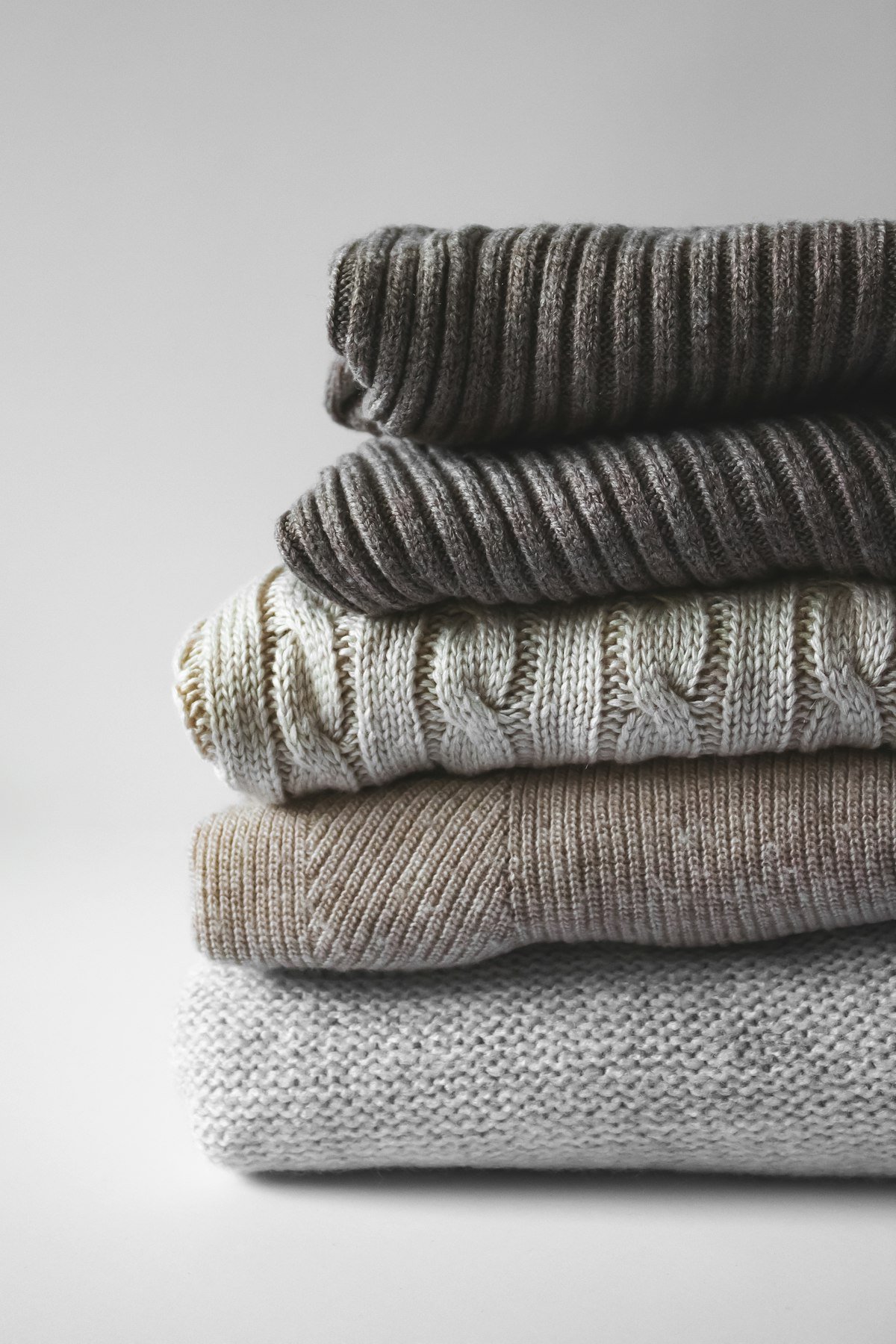 Neatly folded sweaters stacked on a closet shelf