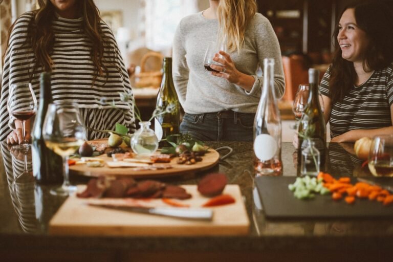 Friends gathered around a kitchen spread with wine at a dinner party