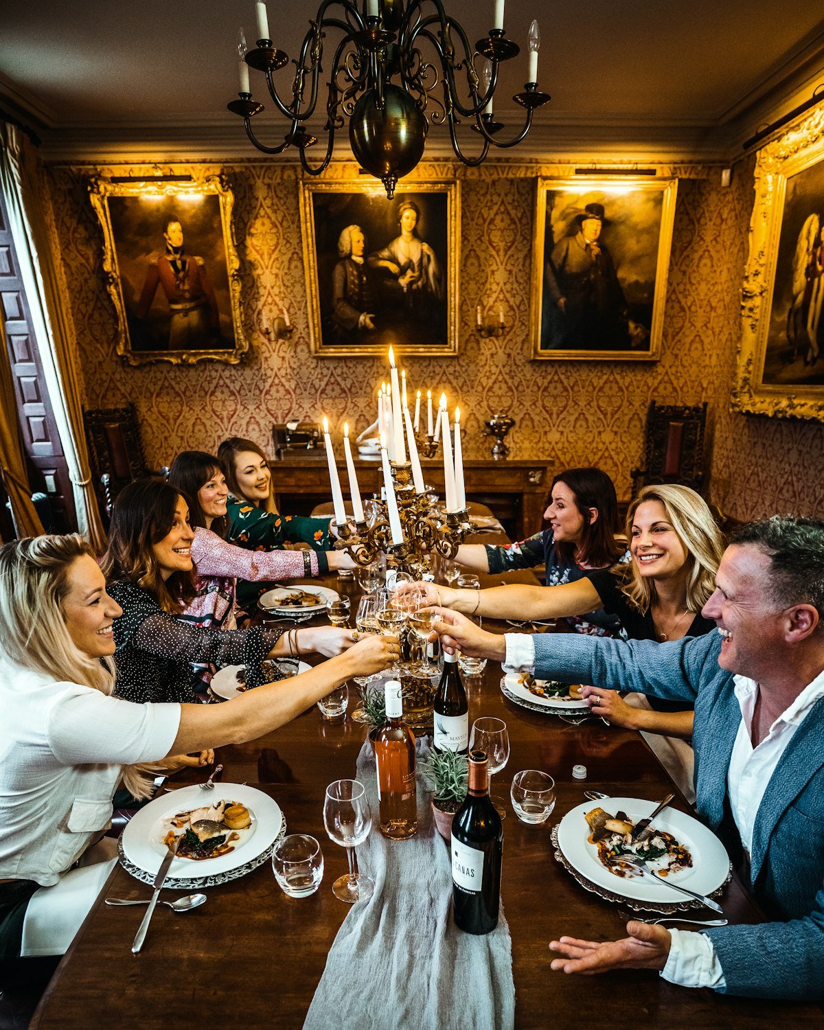 Friends toasting across a candlelit dinner table at home