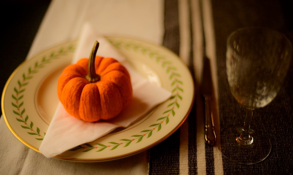 Mini pumpkin resting on a folded napkin at a place setting