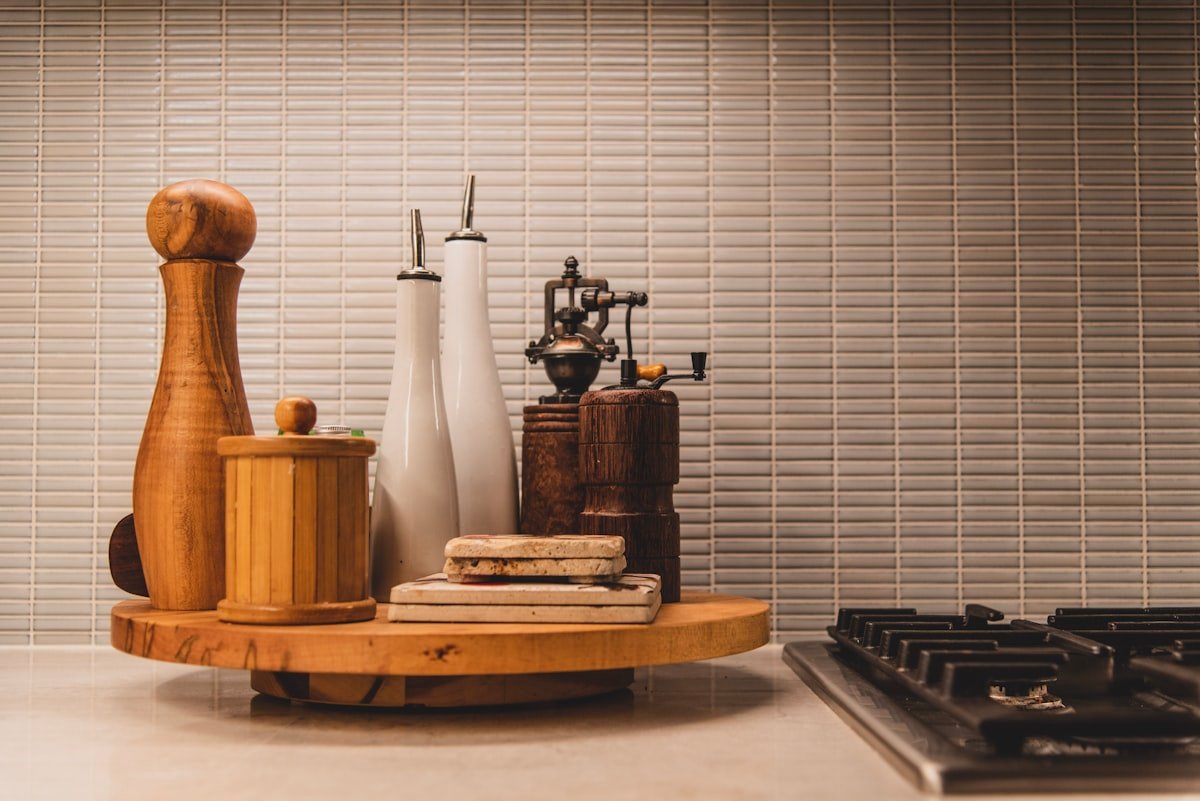 Wooden tray beside the stove corralling oils and pepper mill