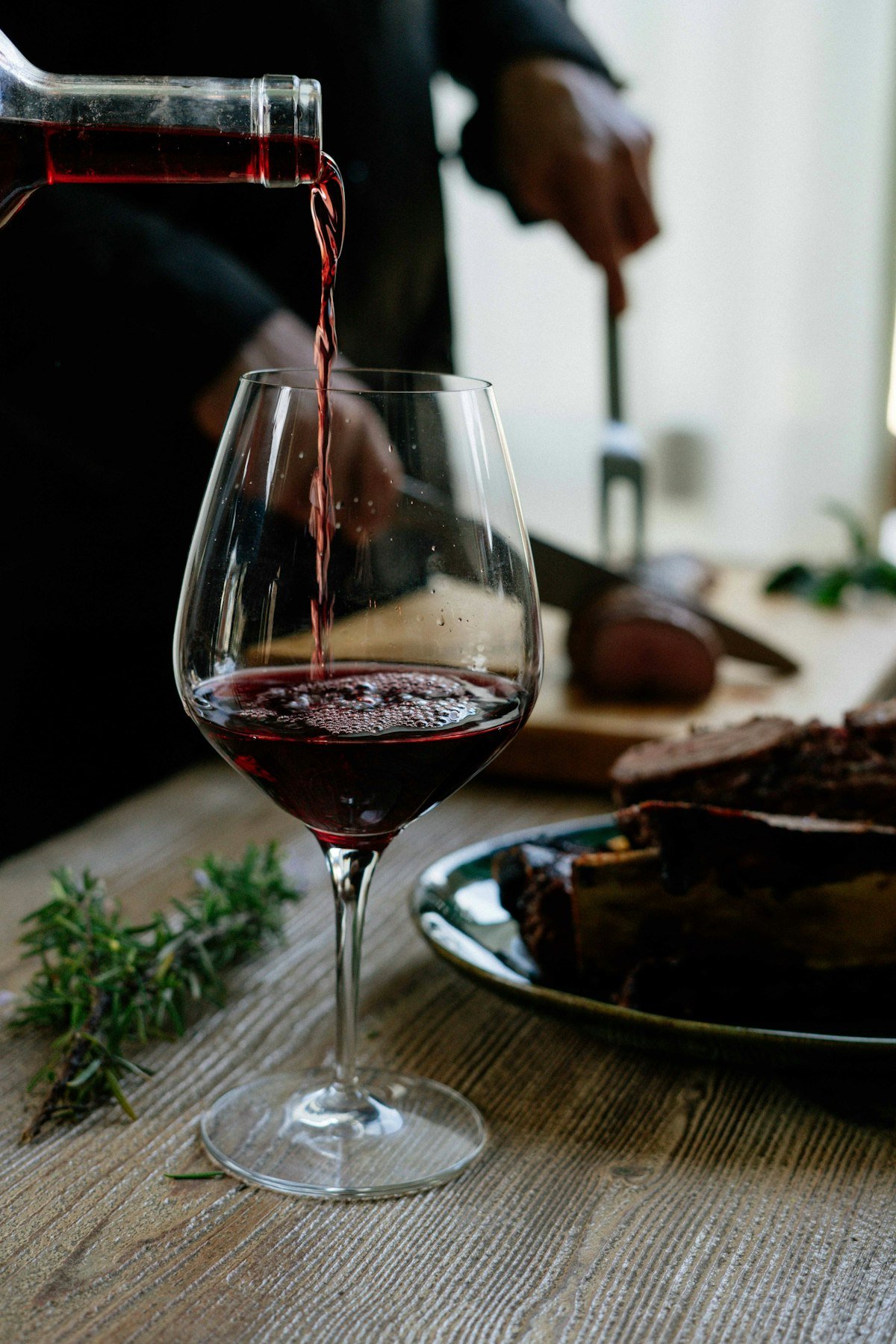 Red wine being poured at a relaxed dinner party