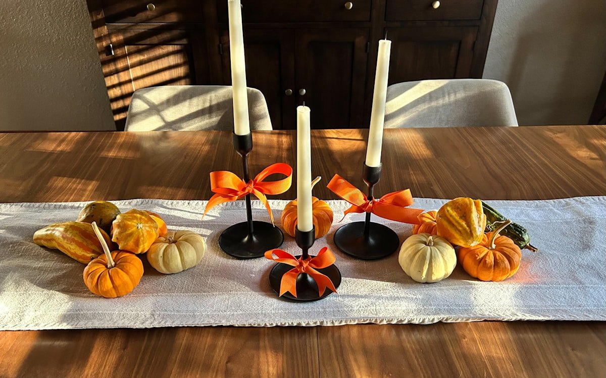 Mini pumpkins and candles running down the center of a wooden table