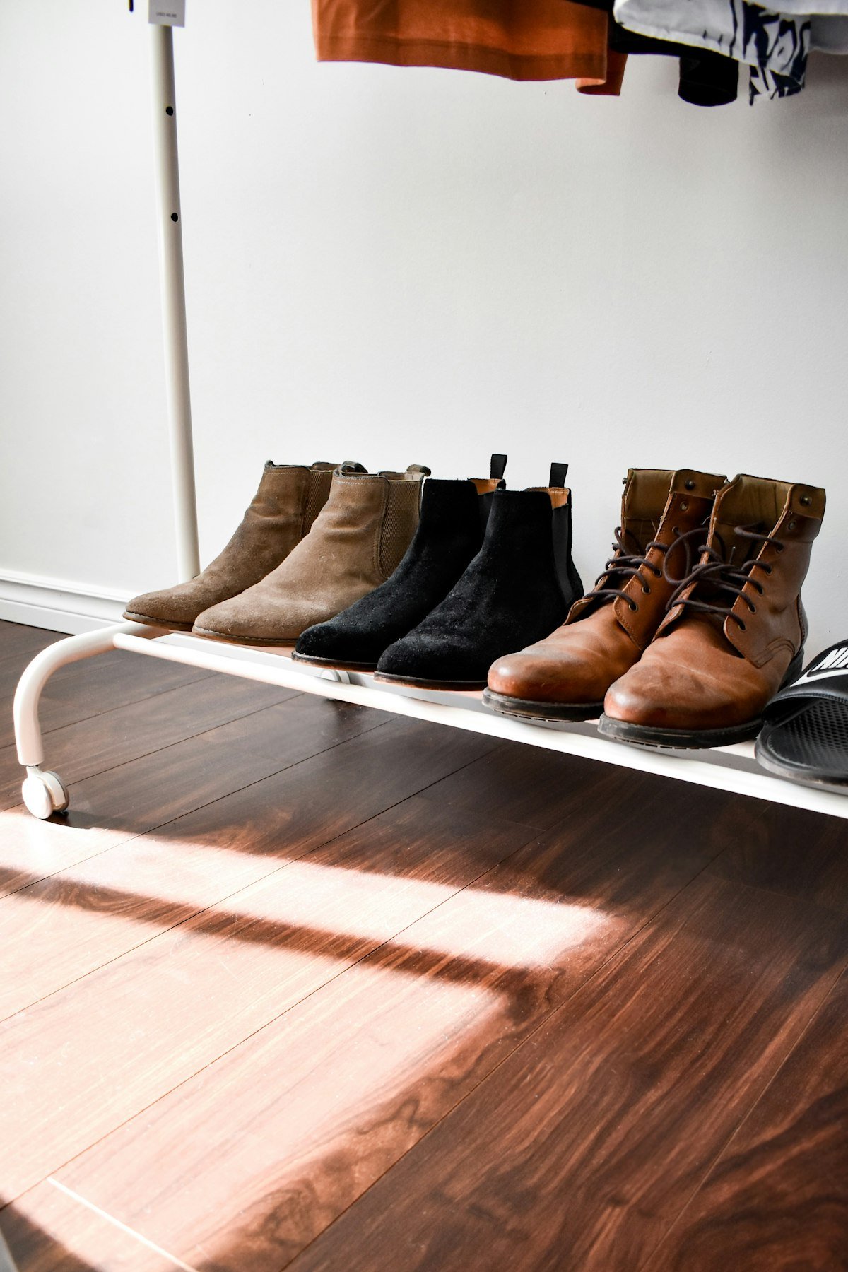 Boots lined up on a low shoe rack on the closet floor