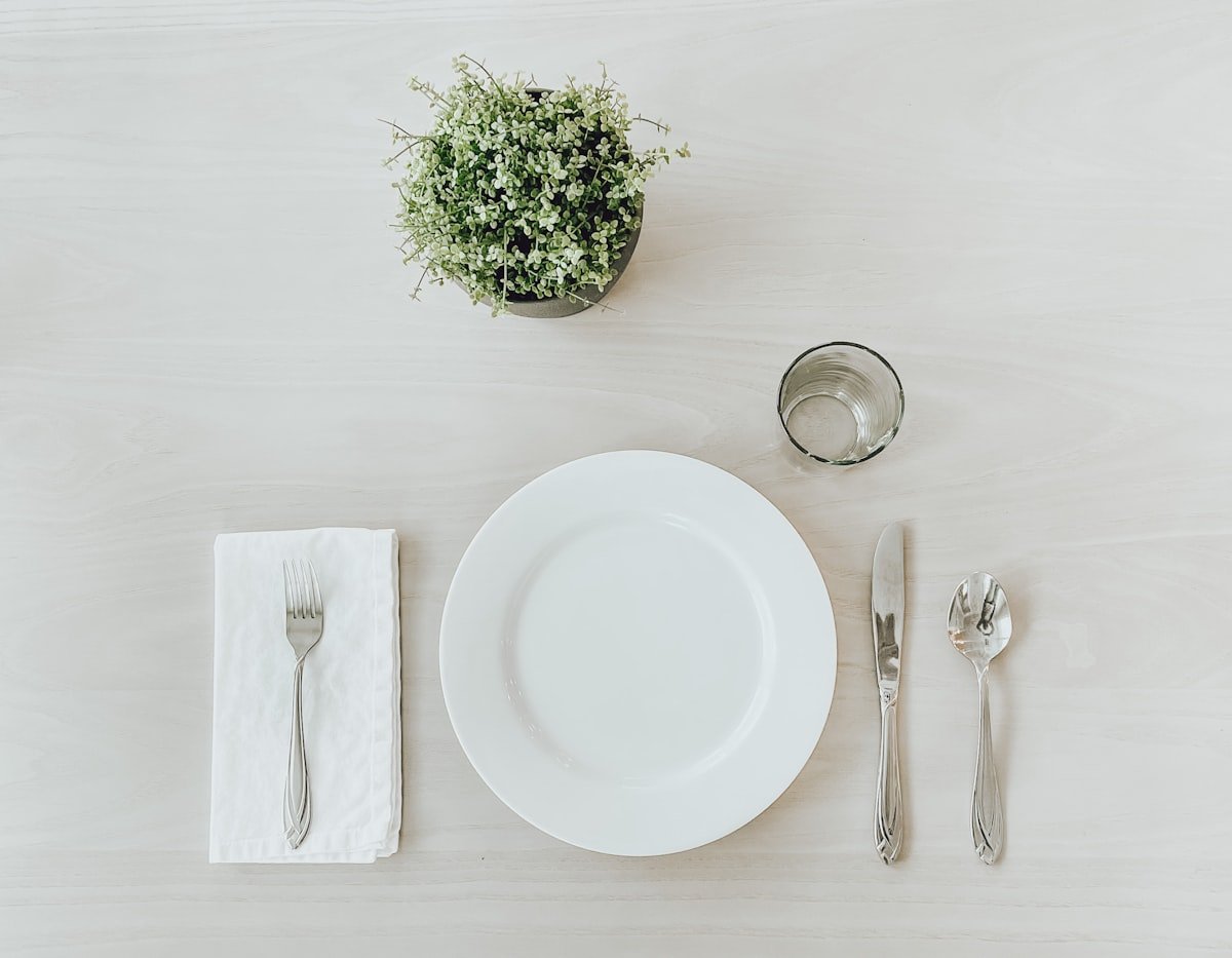 Simple white place setting with a napkin and fresh greenery