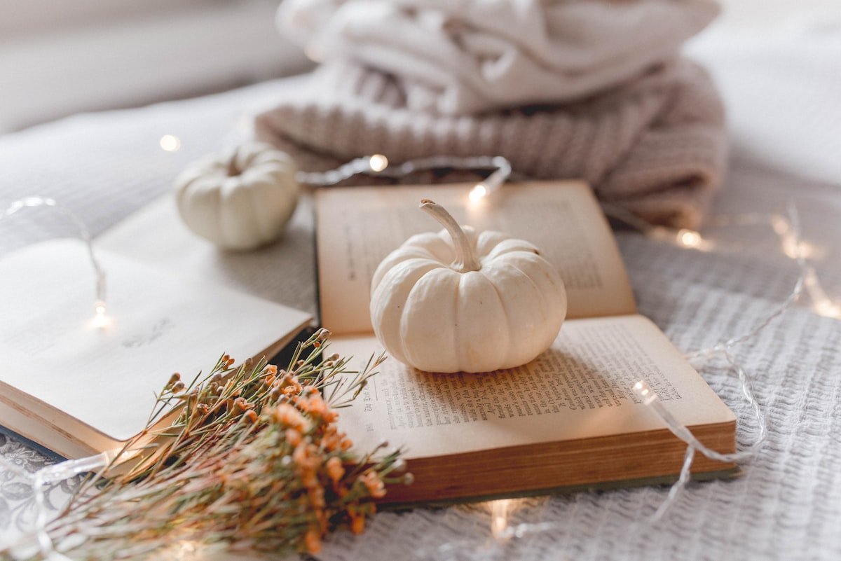White pumpkin on a stack of old books with fairy lights