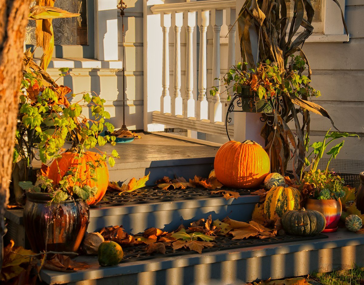 Porch glowing at dusk with lantern light and pumpkins