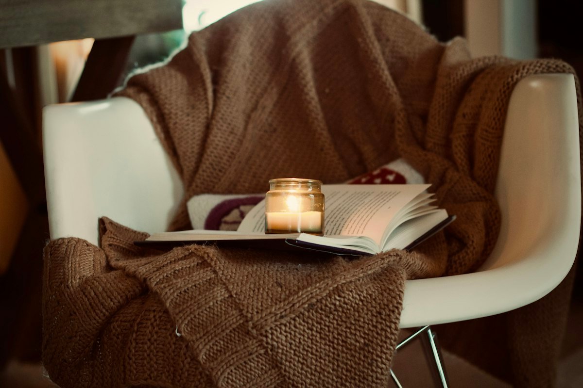 Porch chair layered with a cozy brown throw and warm candle